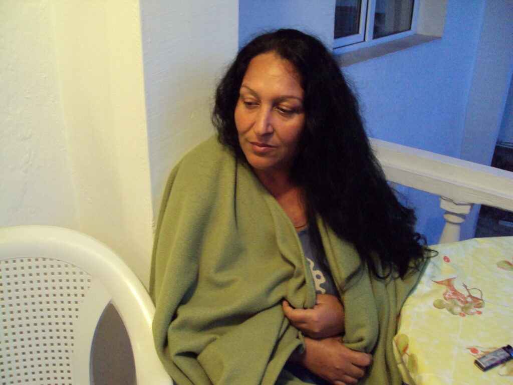 Portrait of Stefka Stefanova Nikolova wrapped in a green blanket, looking down with a pensive expression.